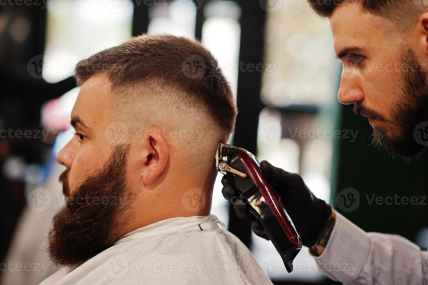 hübscher bärtiger mann im friseursalon, friseur bei der arbeit. foto