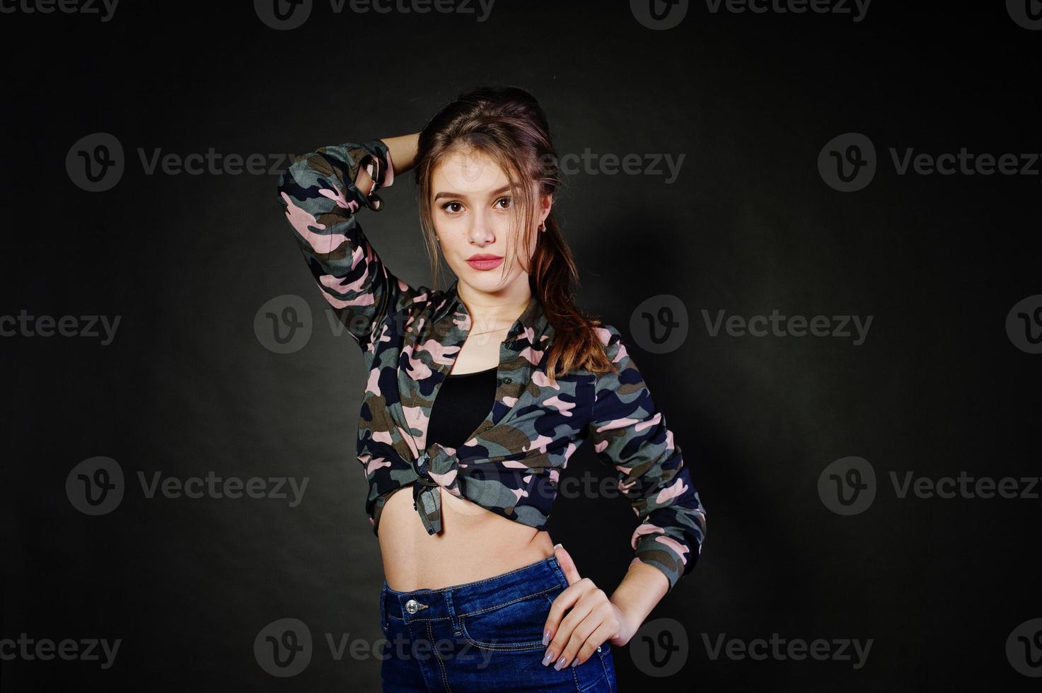 hübsches brünettes mädchen trägt militärisches hemd und jeans und posiert im studio vor grauem hintergrund. Studio-Model-Porträt. foto