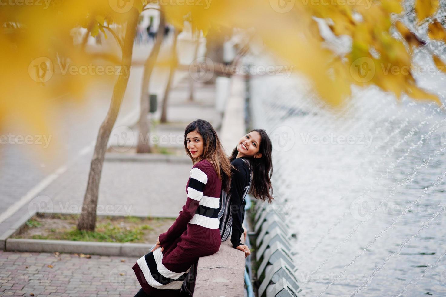 Porträt von zwei jungen schönen indischen oder südasiatischen Mädchen im Teenageralter im Kleid im Herbstpark gestellt. foto