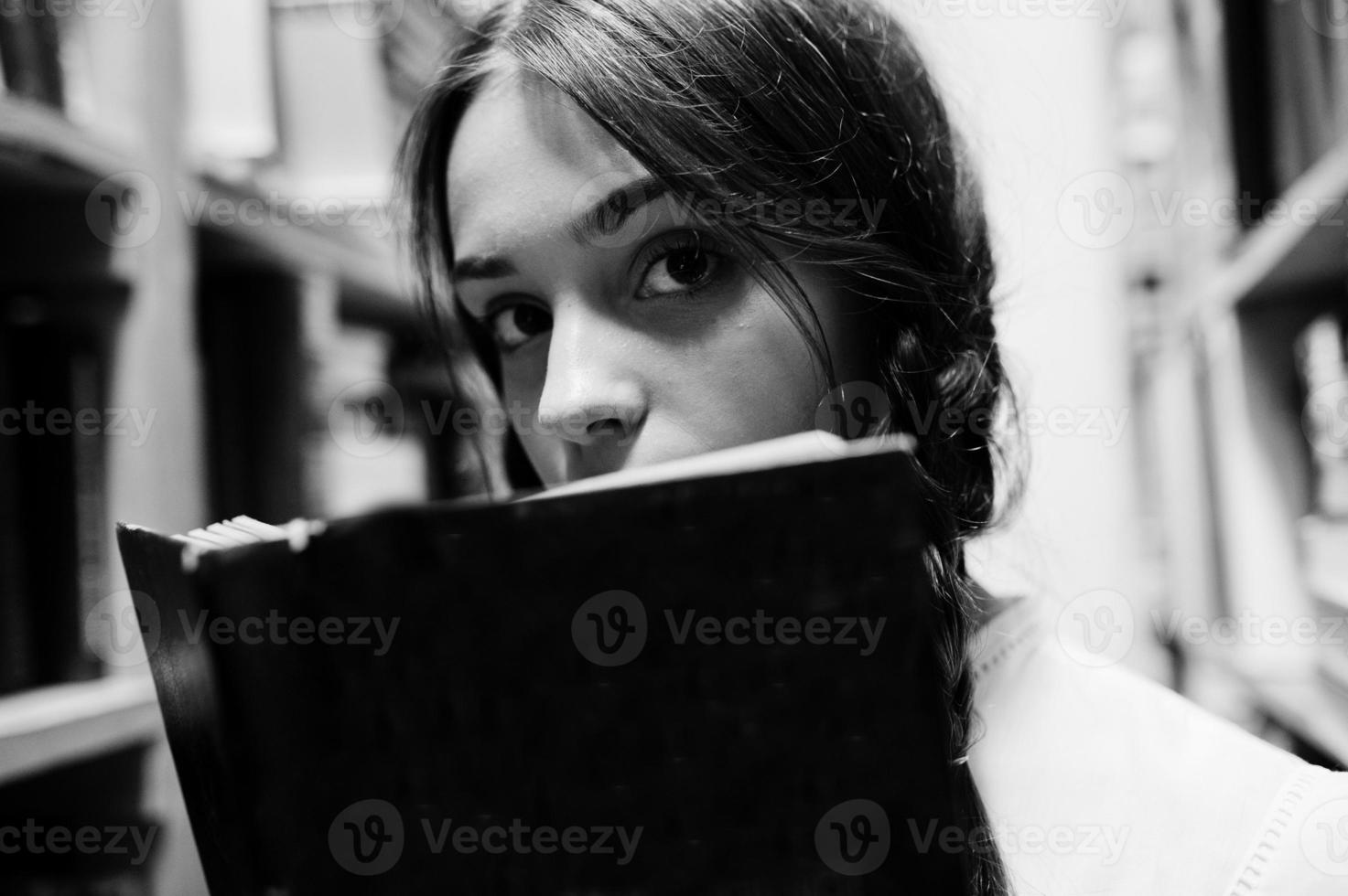 Mädchen mit Zöpfen in weißer Bluse in der alten Bibliothek. foto