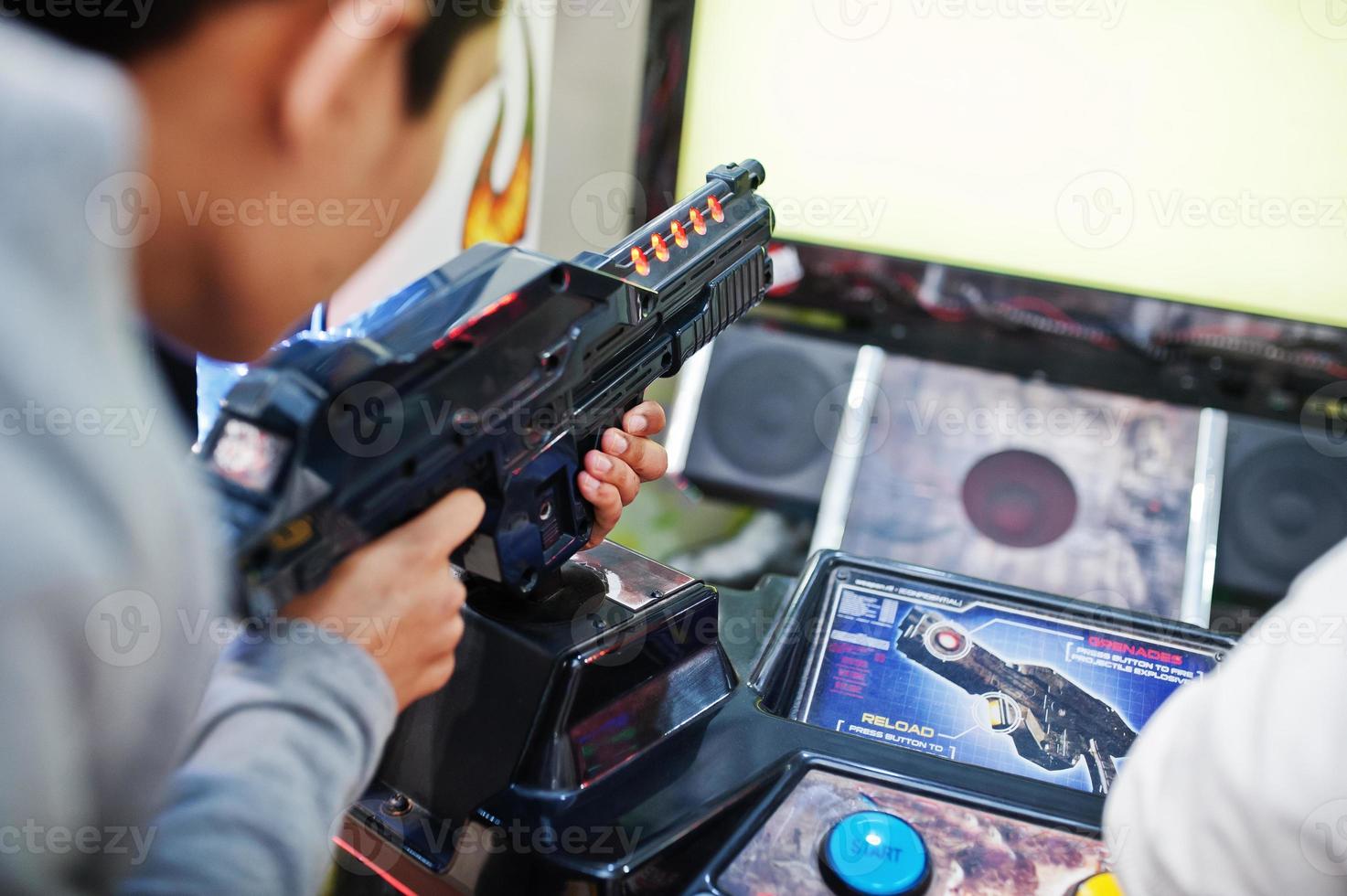 Zwei Asiaten treten auf einem Shooter-Simulator-Arcade-Spiel gegeneinander an. foto