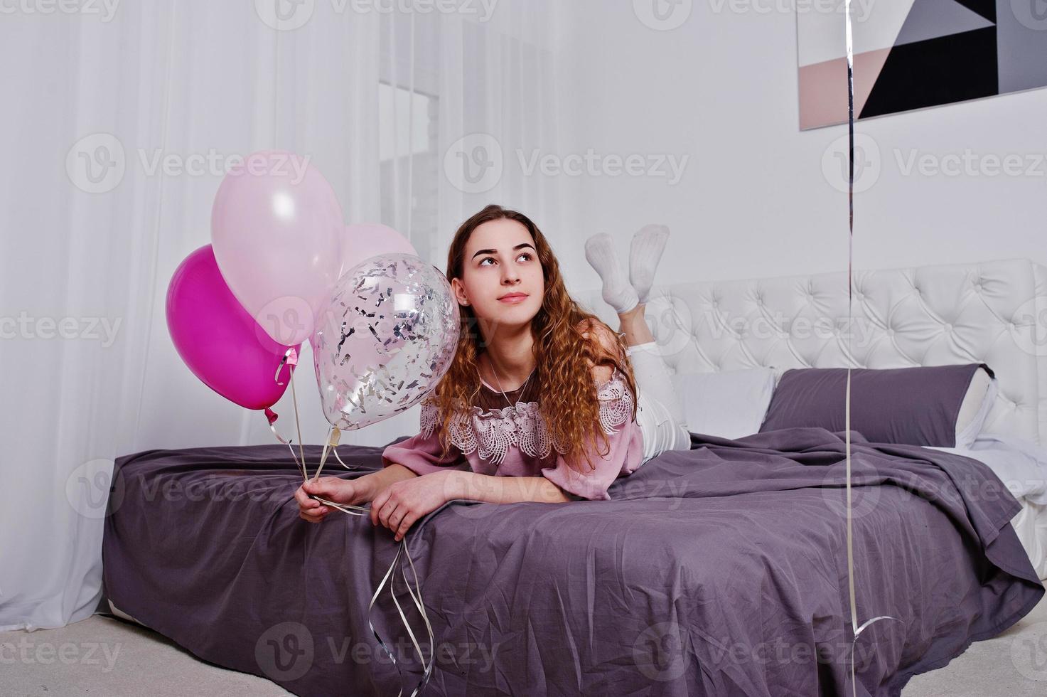 junges mädchen mit luftballons auf dem bett posierte im studiozimmer. foto
