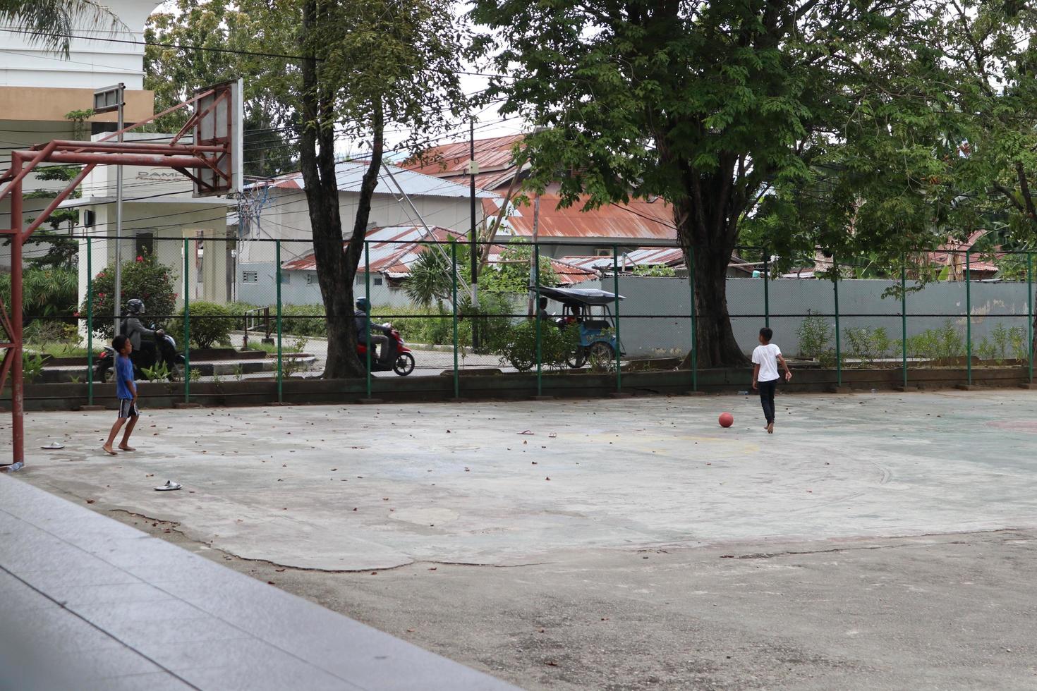 gorontalo-indonesien, juni 2022 - kinder üben tagsüber fußball auf einem basketballplatz foto