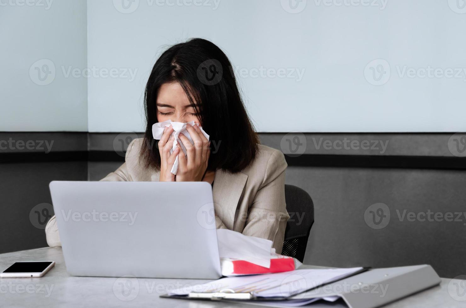 junge geschäftsfrau, die während der arbeit im tagungsraum niest. arbeits- und saisonales wendekonzept foto