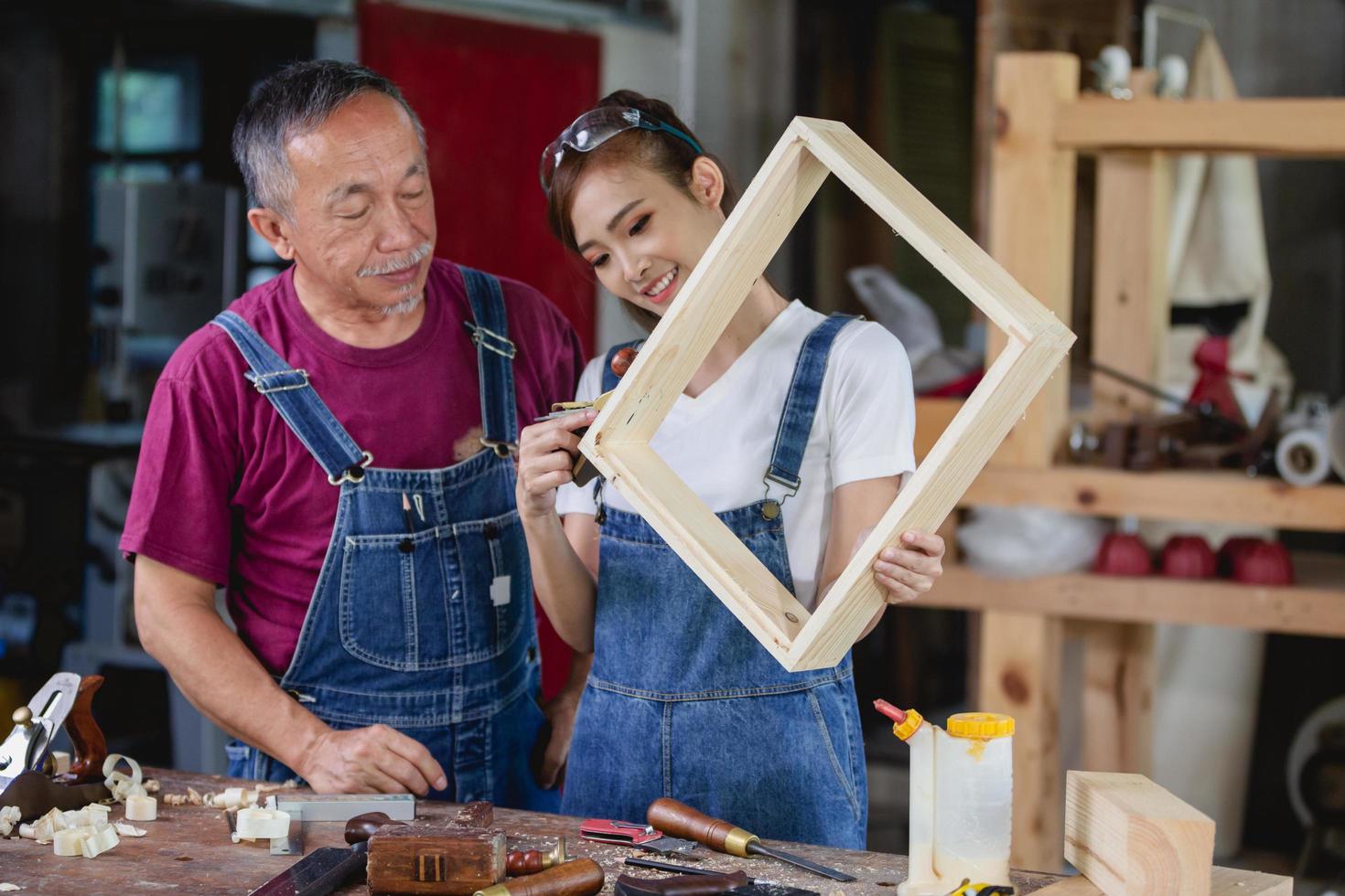 eine Zimmermannsfrau und ein Zimmermann arbeiten in ihrer eigenen Holzwerkstatt. Tischlerarbeiten an Holzbrettern in der Werkstatt. Konzept für kleine Unternehmen foto