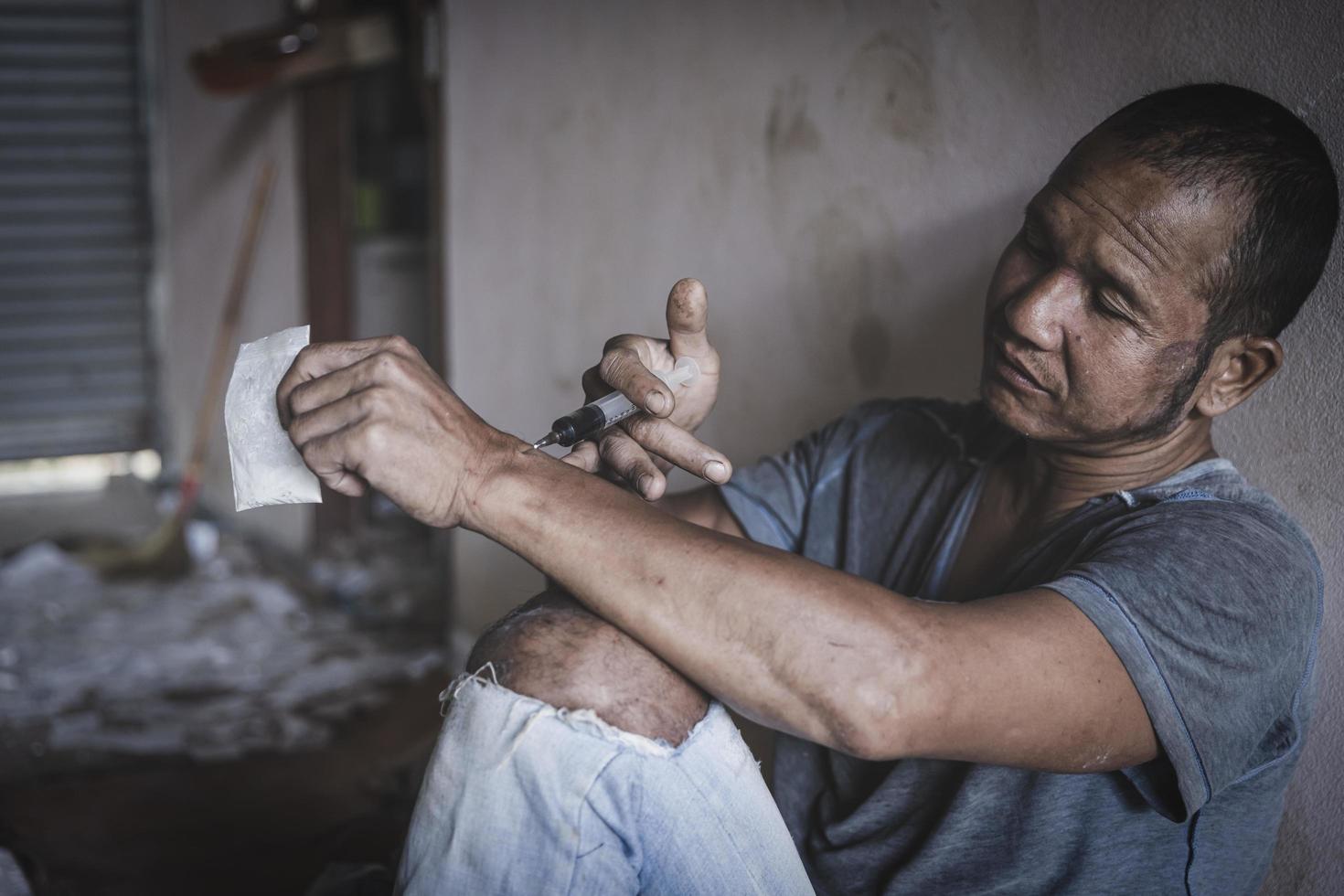 mann drogenabhängiger injiziert heroin in seinen arm, drogenabhängiger mann mit spritze mit drogen, drogenkonzept, 26. juni, internationaler tag gegen drogenmissbrauch. foto