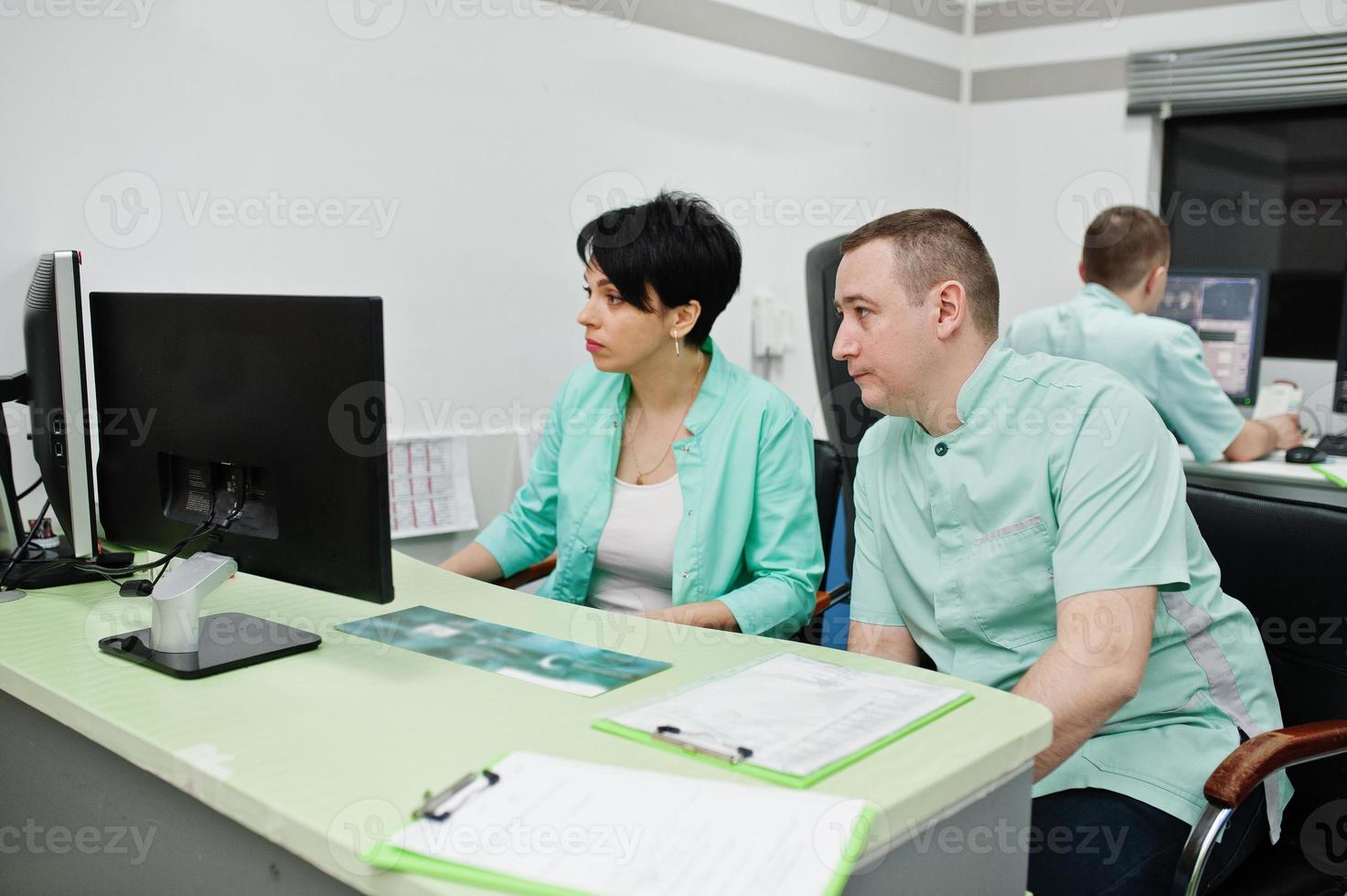 medizinisches Thema. Zwei Ärzte treffen sich im MRT-Büro des Diagnosezentrums im Krankenhaus und sitzen in der Nähe von Computermonitoren. foto