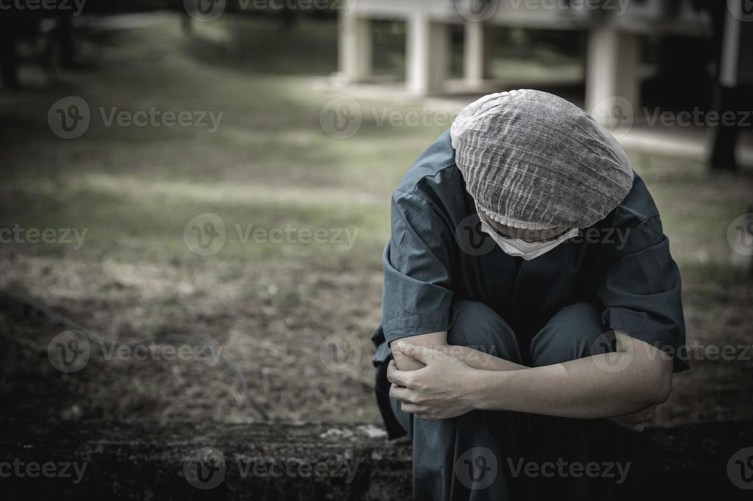 müde depressive asiatische krankenschwester trägt gesichtsmaske blaue uniform sitzt auf dem krankenhausboden, junge ärztin gestresst von harter arbeit foto