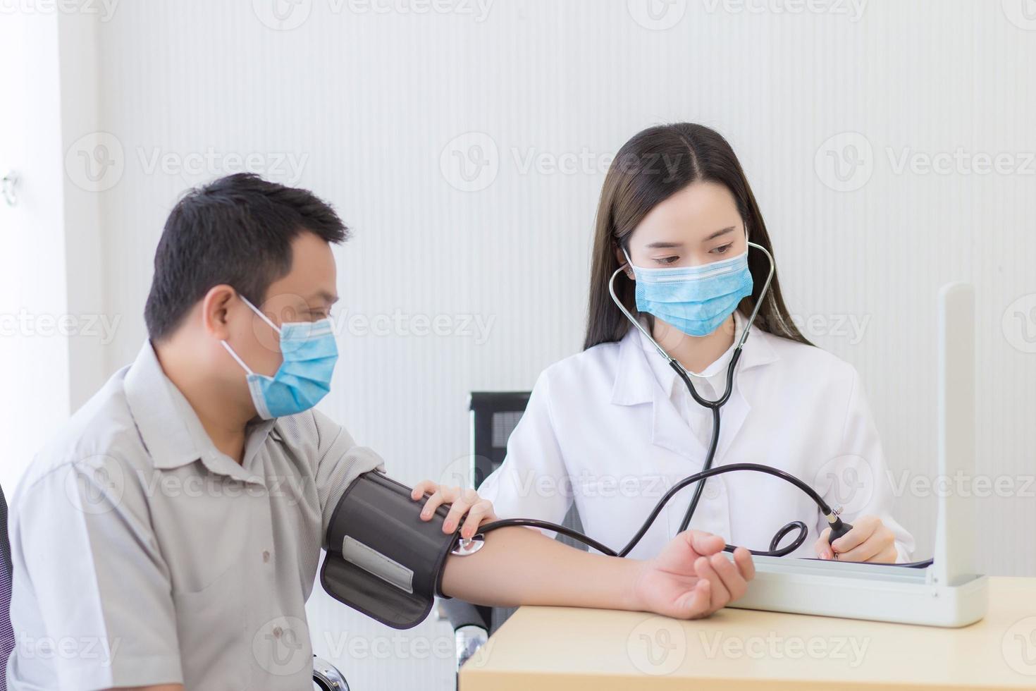 asiatische Ärztin misst den Blutdruck eines männlichen Patienten foto