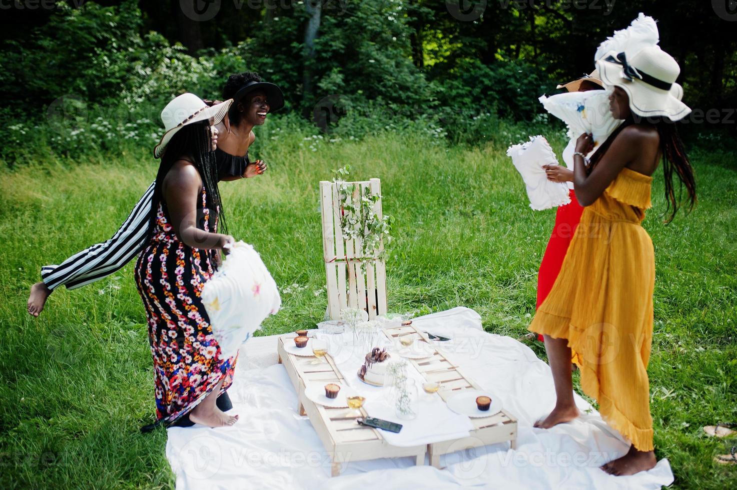 gruppe afroamerikanischer mädchen, die geburtstagsfeier feiern und spaß mit kissen im freien mit dekor haben. foto