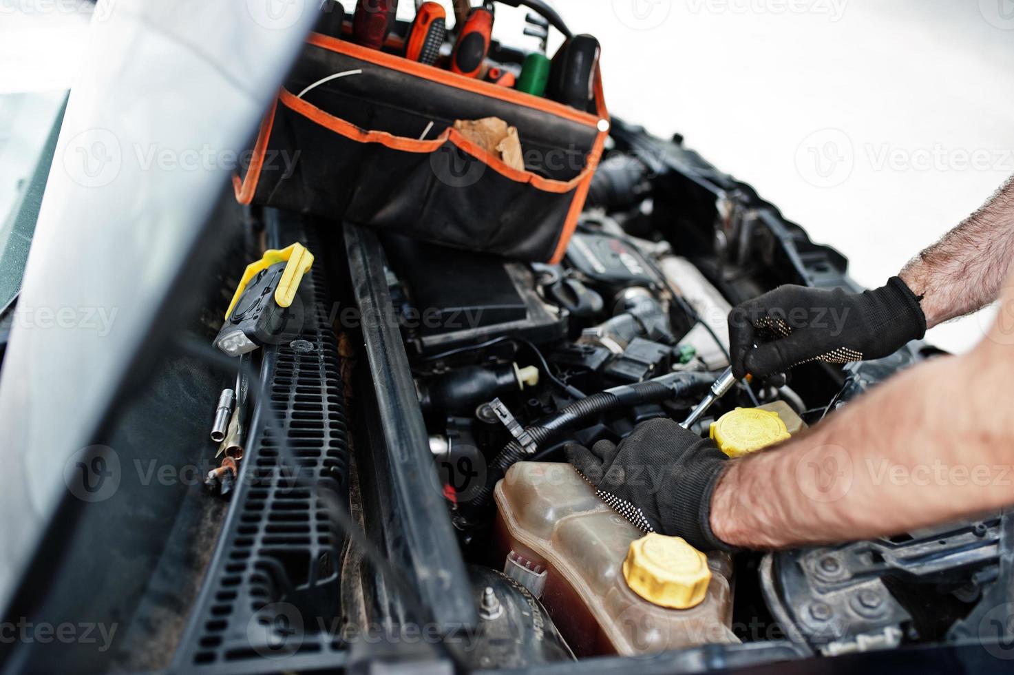 Thema Autoreparatur und -wartung. mechaniker in uniform, der im autoservice arbeitet und den motor überprüft. foto