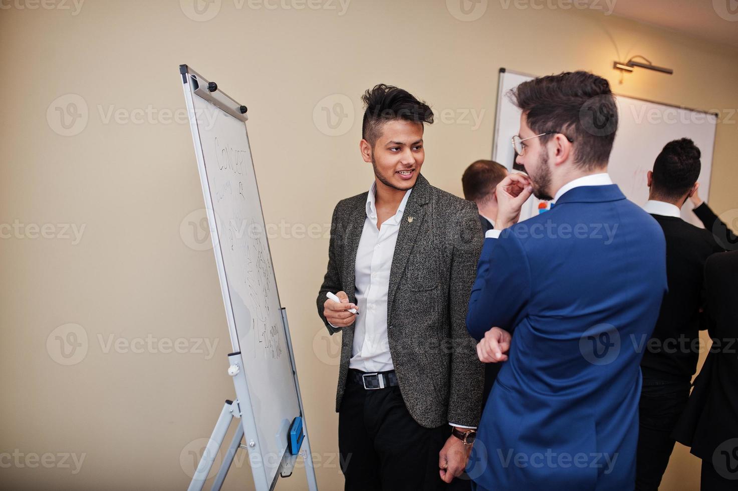 männliche kollegen, die im team arbeiten, kooperieren, multirassische mitarbeitergruppe konzentrierte sich auf die projektplanung gegen flipchart-tafel und die diskussion von ideen. foto