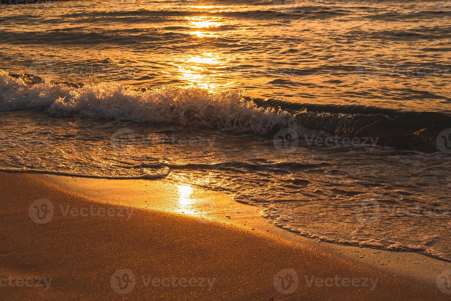 Wellen an einem Sandstrand bei Sonnenuntergang foto