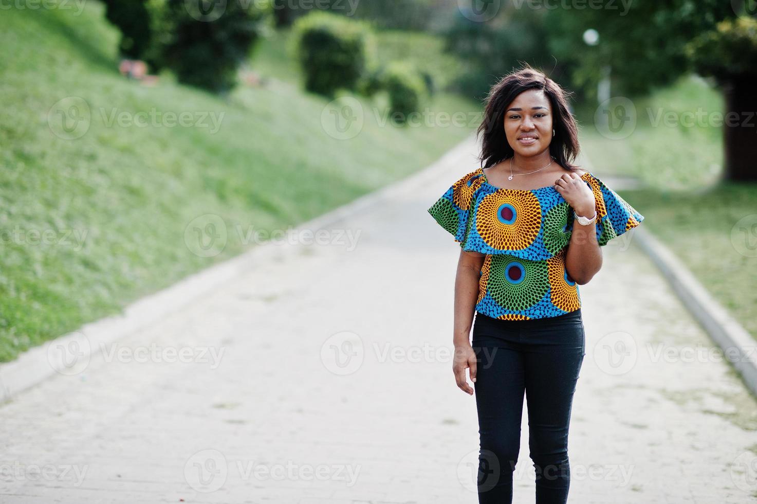 Afroamerikanisches Mädchen in farbigem Hemd und schwarzer Hose posierte im Freien. modische schwarze Frau. foto