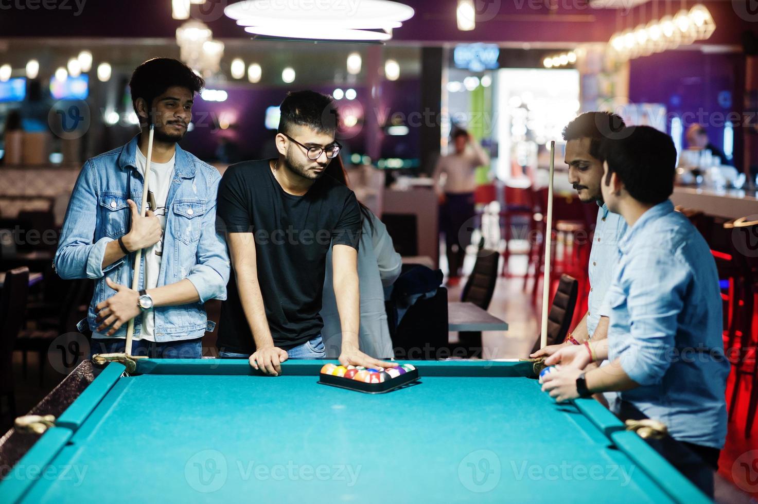 Eine Gruppe stilvoller asiatischer Freunde trägt Jeans und spielt Billard an der Bar. foto