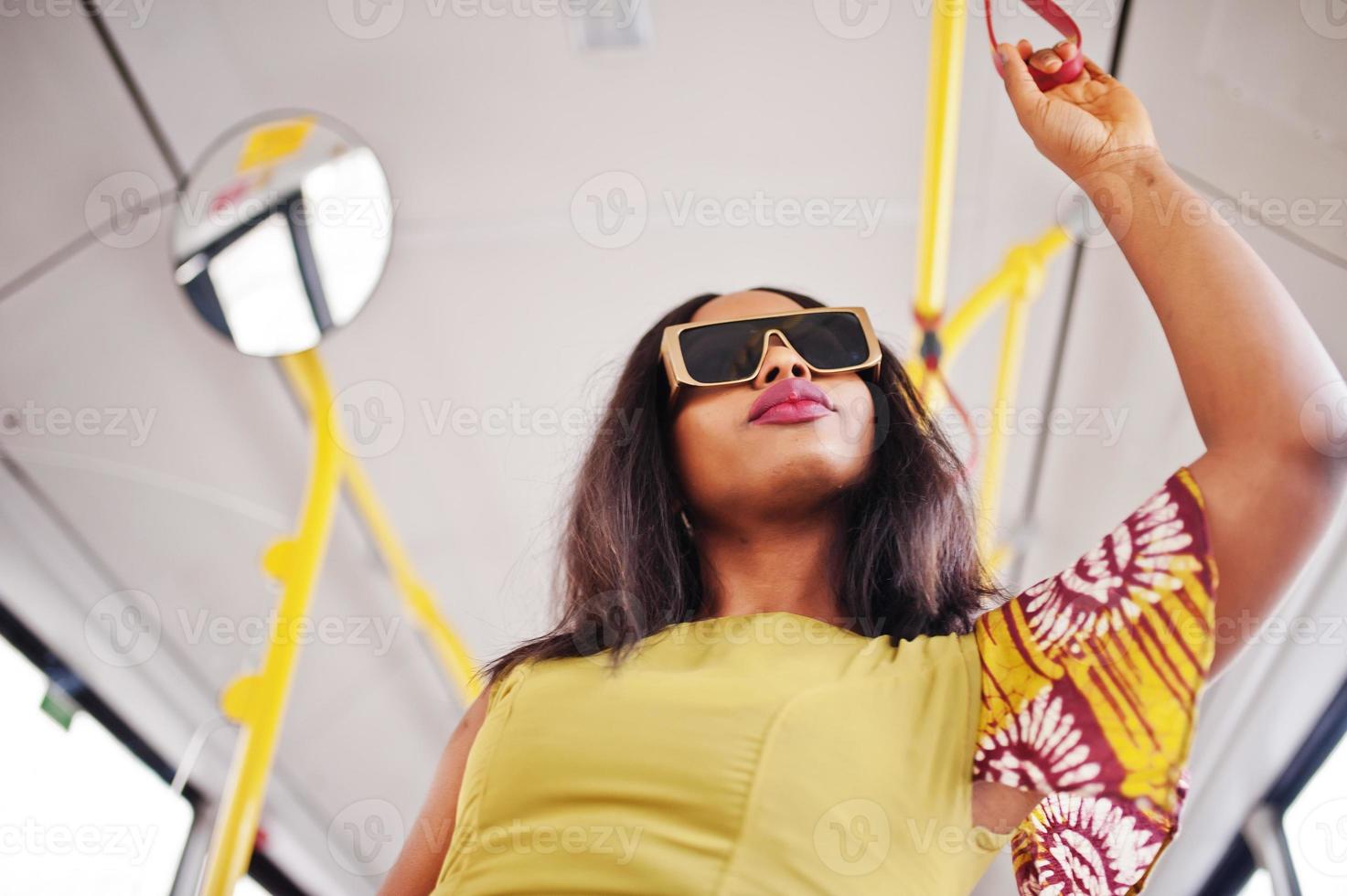 junge stilvolle afroamerikanerin in moderner sonnenbrille, die in einem bus fährt. foto
