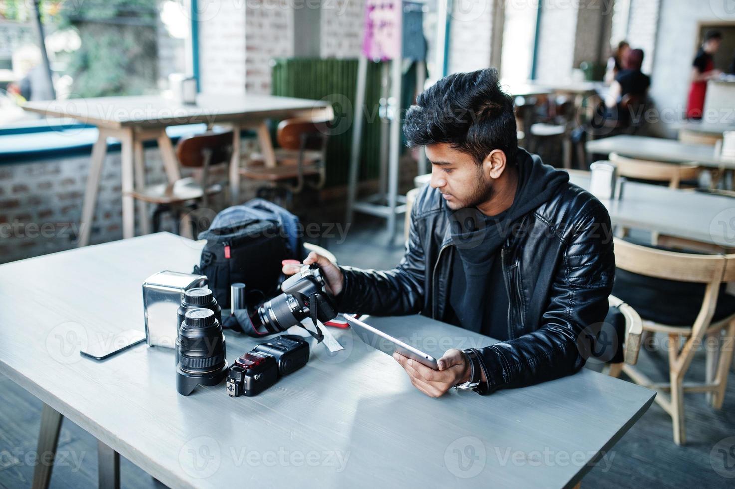 intelligenter junger asiatischer Fotograf, der mit Tablet arbeitet, während er im Café sitzt. foto