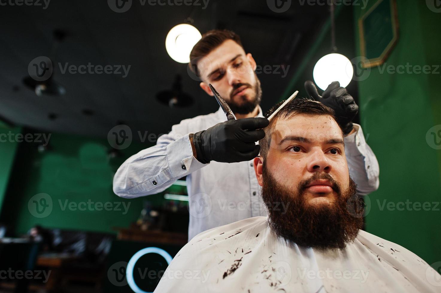 hübscher bärtiger mann im friseursalon, friseur bei der arbeit. foto