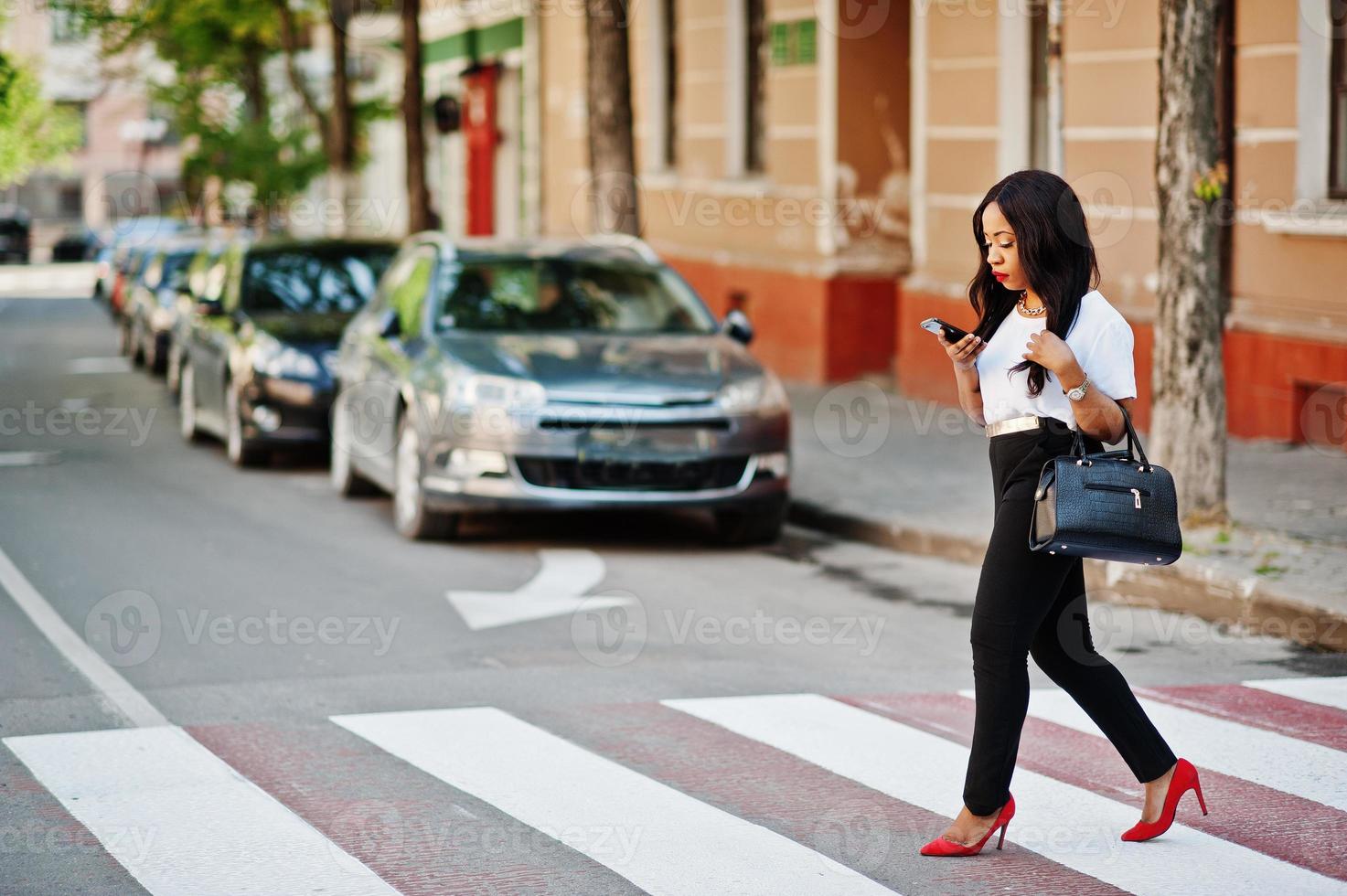 Stilvolle afroamerikanische Geschäftsfrau auf den Straßen der Stadt am Fußgängerüberweg. foto