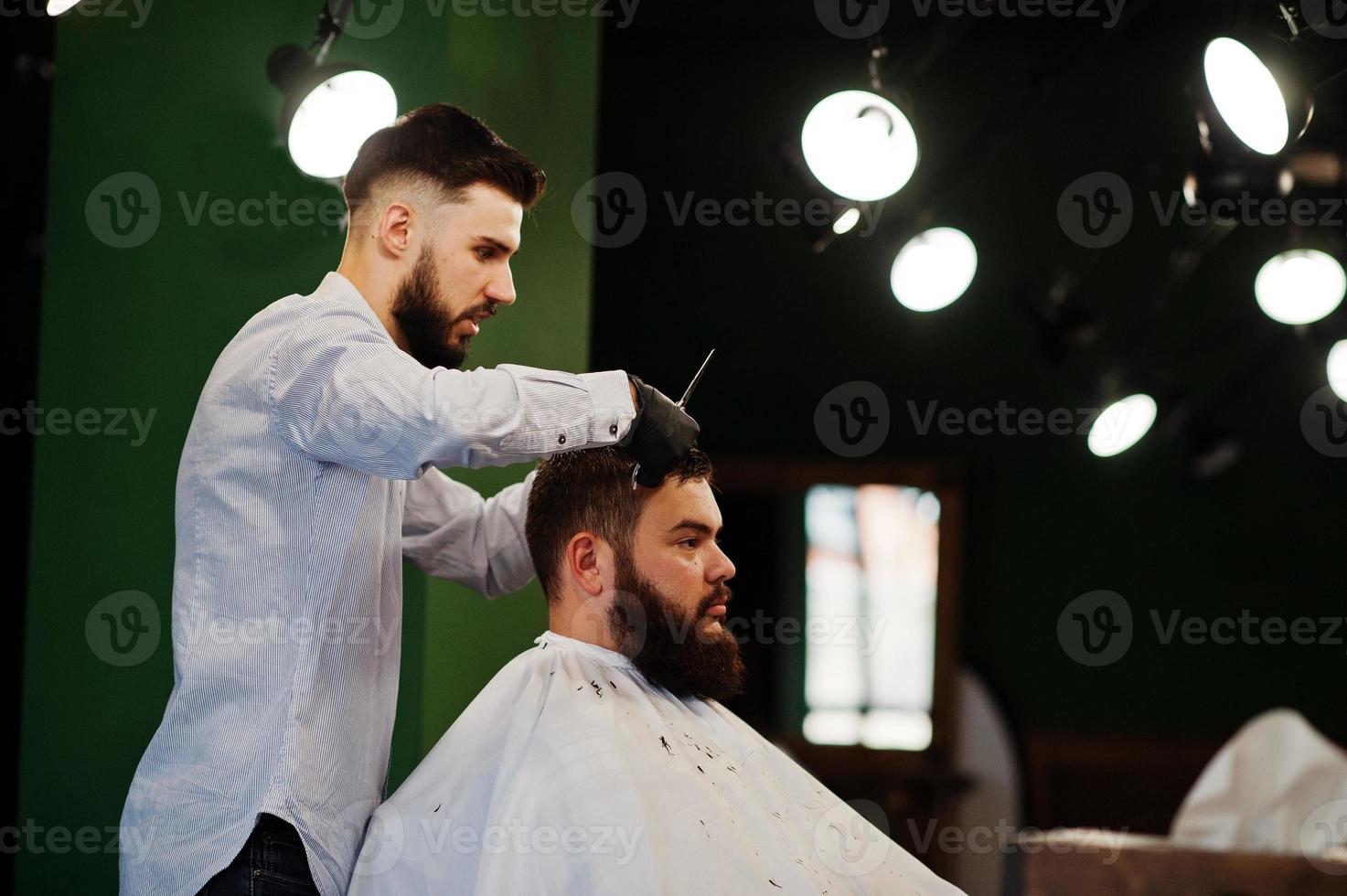 hübscher bärtiger mann im friseursalon, friseur bei der arbeit. foto