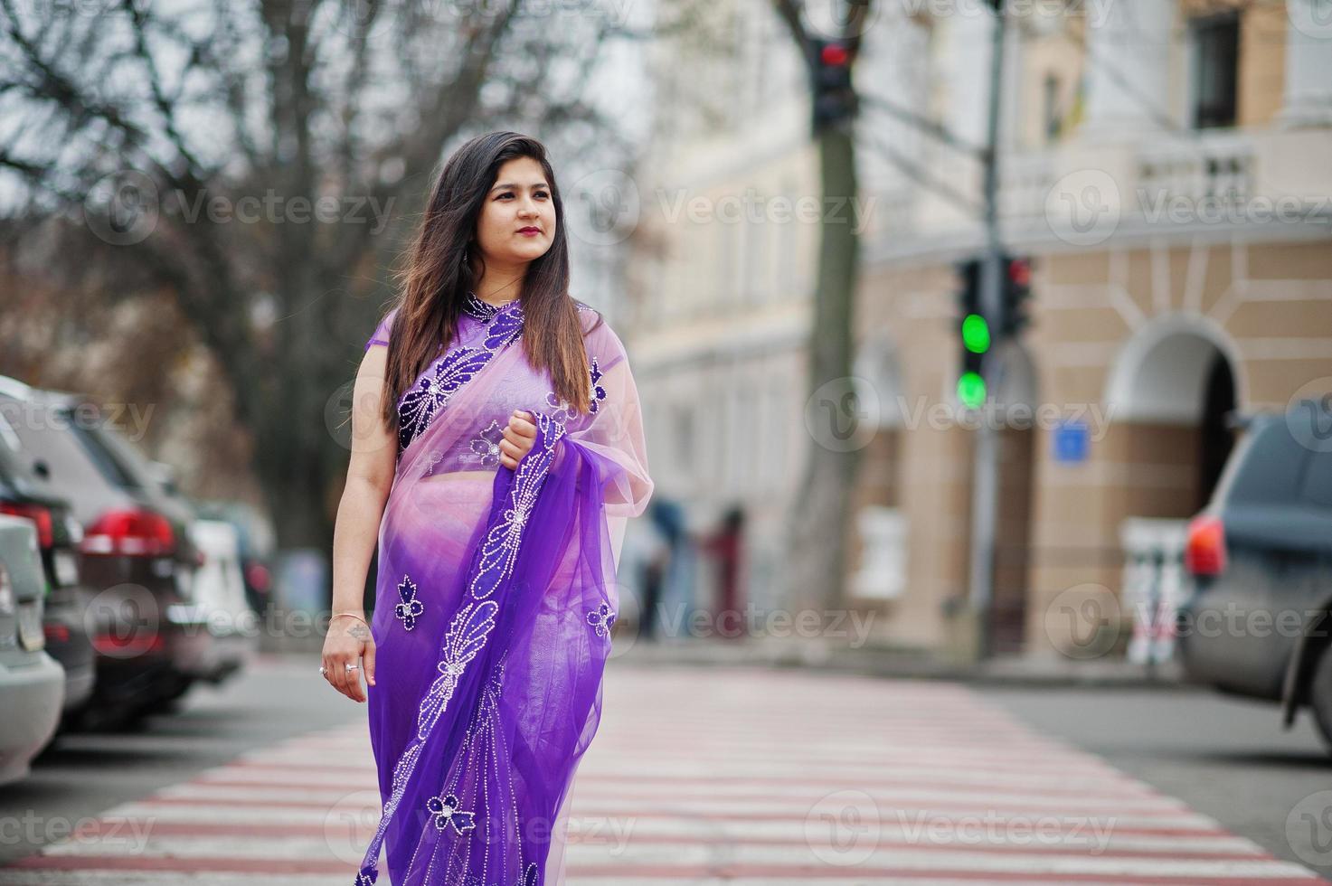 Indisches hinduistisches Mädchen im traditionellen violetten Saree posierte auf der Straße und ging am Fußgängerüberweg. foto