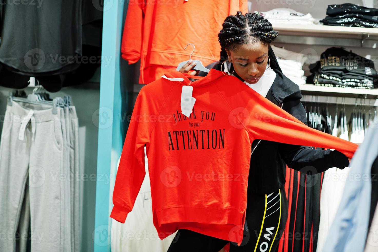 afrikanisch-amerikanische Frauen in Trainingsanzügen, die im Sportswear-Einkaufszentrum gegen Regale mit Sweatshirt einkaufen. Sportgeschäft Thema. foto