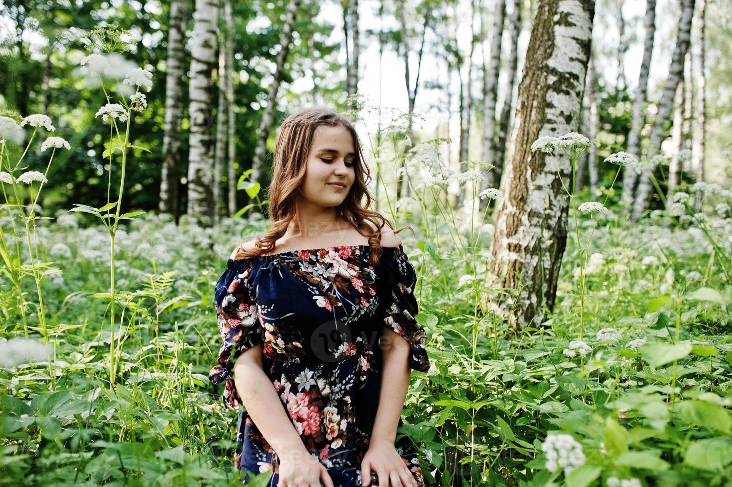 Porträt eines fabelhaften jungen Mädchens in hübschem Kleid mit stilvoller lockiger Frisur, das im Wald oder Park posiert. foto