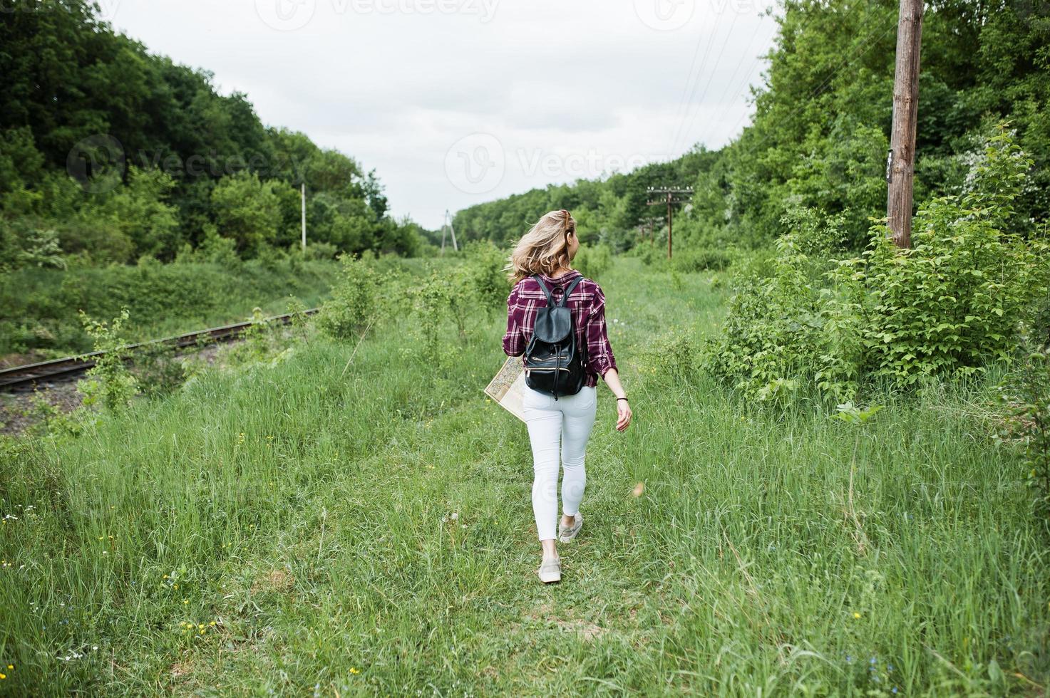 Porträt eines schönen blonden Mädchens im Tartanhemd, das mit einer Karte auf dem Land spazieren geht. foto