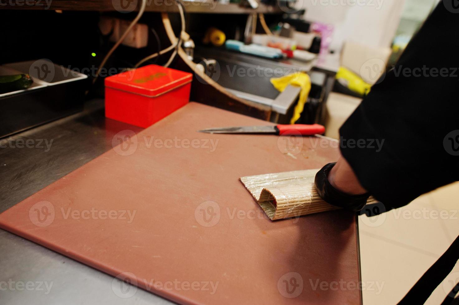 Nahaufnahme der Hände professioneller Köche in schwarzen Handschuhen, die Sushi und Brötchen in einer Restaurantküche mit japanischer traditioneller Küche zubereiten. foto