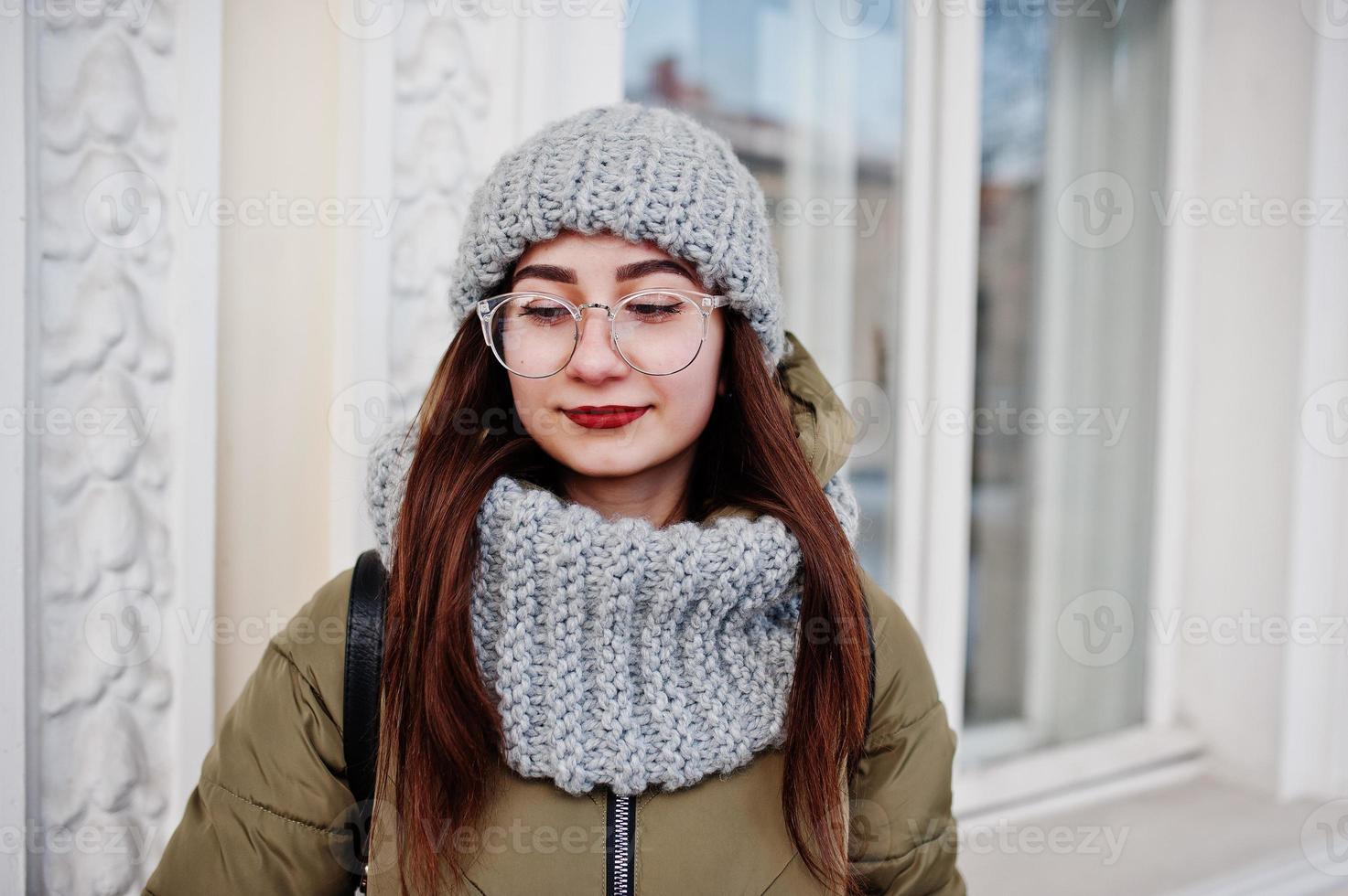 Porträt eines brünetten Mädchens in grauem Schal und Hut, Brille bei kaltem Wetter. foto