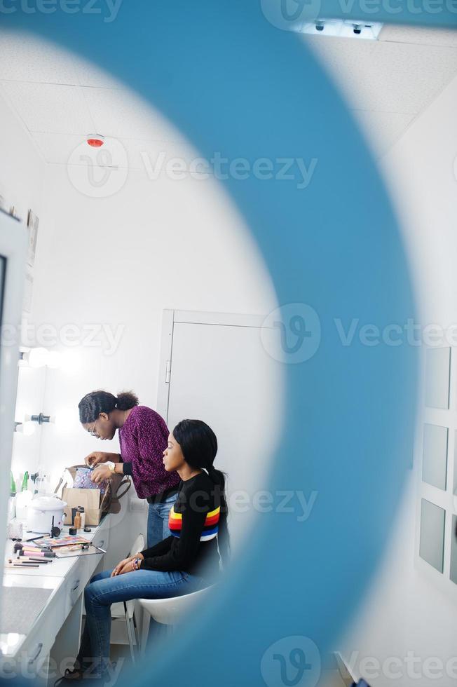 Afroamerikanerin beim Schminken durch Make-up-Künstlerin im Schönheitssalon. foto