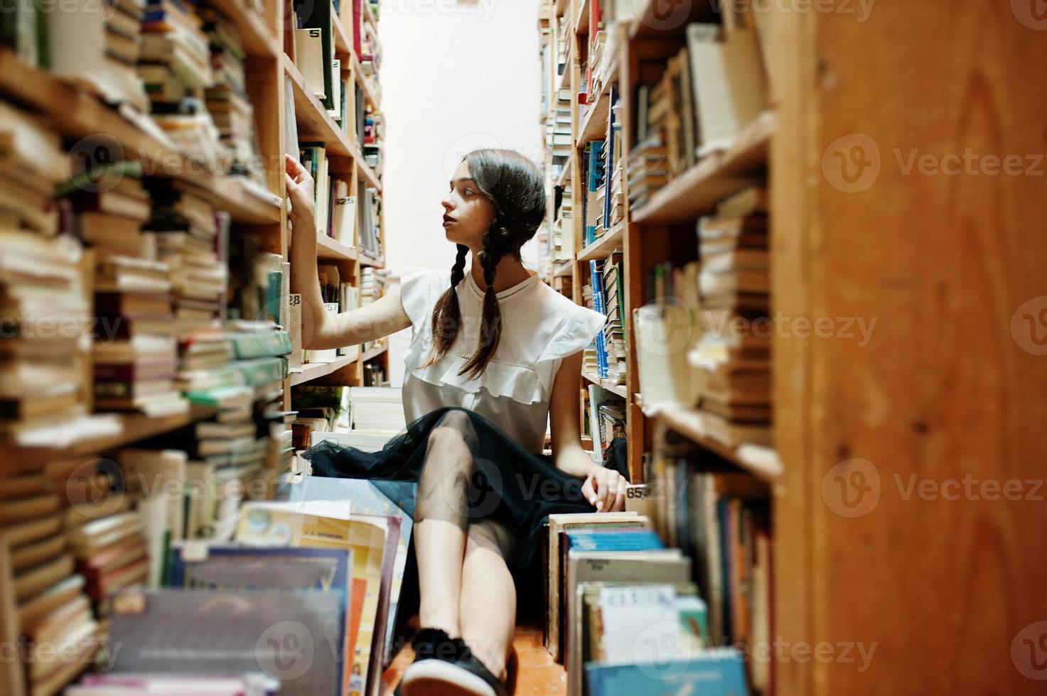 Mädchen mit Zöpfen in weißer Bluse in der alten Bibliothek. foto