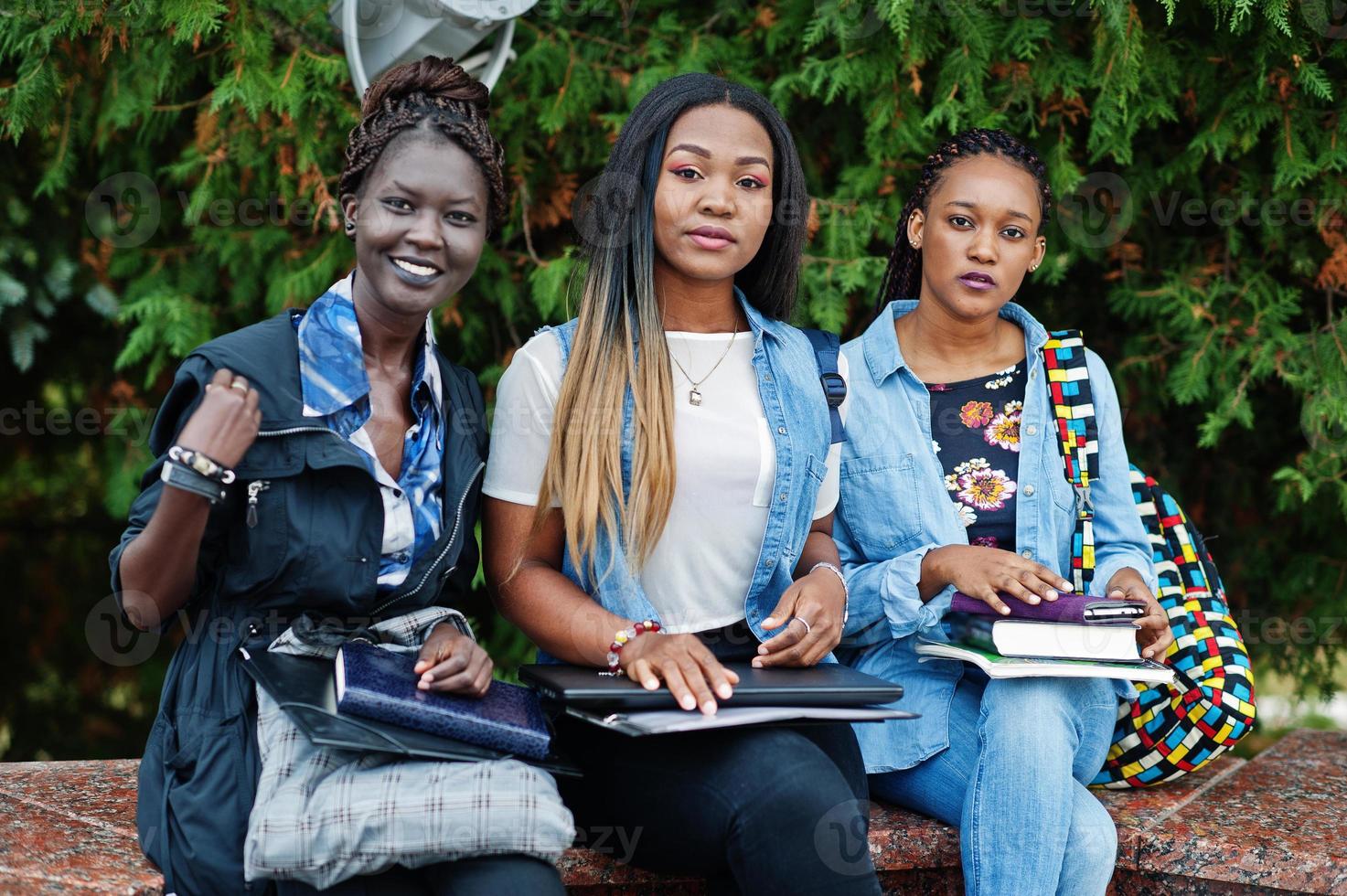 Drei afrikanische Studentinnen posierten mit Rucksäcken und Schulsachen auf dem Hof der Universität. foto