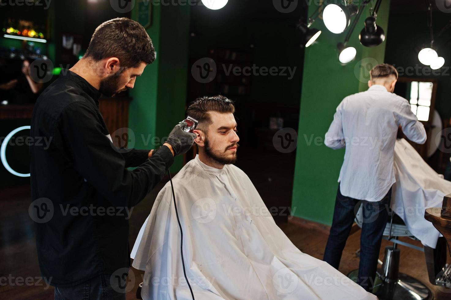 hübscher bärtiger mann im friseursalon, friseur bei der arbeit. foto