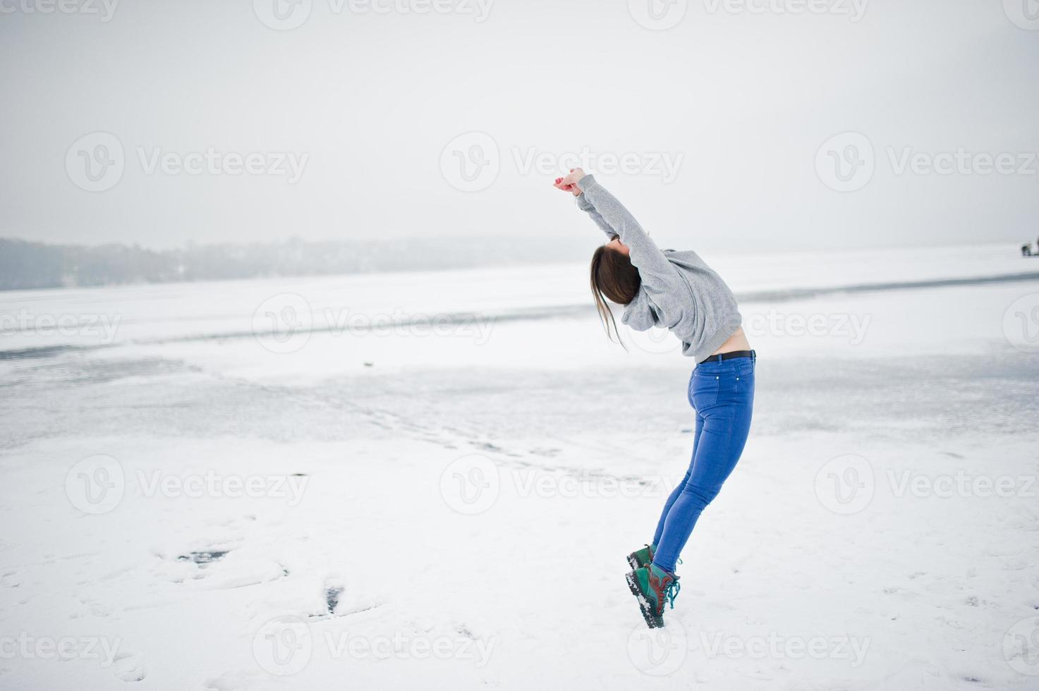 lustiges springendes mädchen auf zugefrorenem see am wintertag. foto