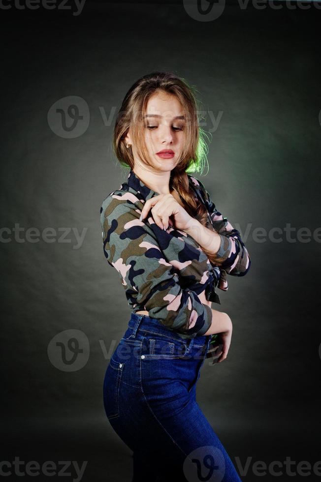 hübsches brünettes mädchen trägt militärisches hemd und jeans und posiert im studio vor grauem hintergrund. Studio-Model-Porträt. foto