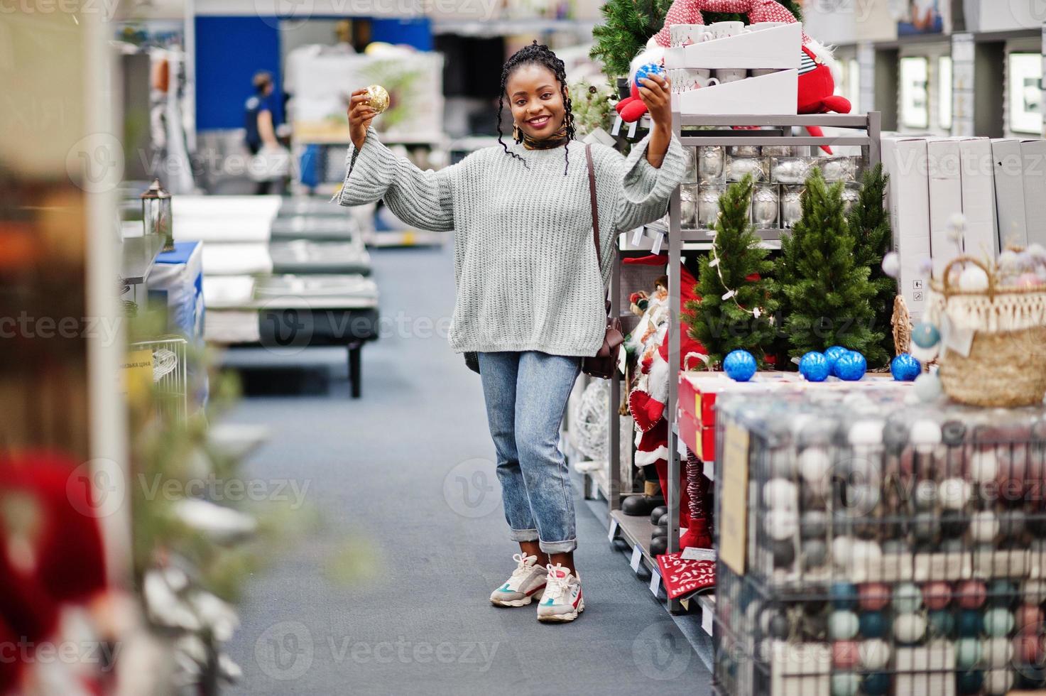 afrikanische frau, die neujahrssachen für ihre wohnung in einem modernen einrichtungsgeschäft auswählt. Einkaufen zum Thema Weihnachten. foto