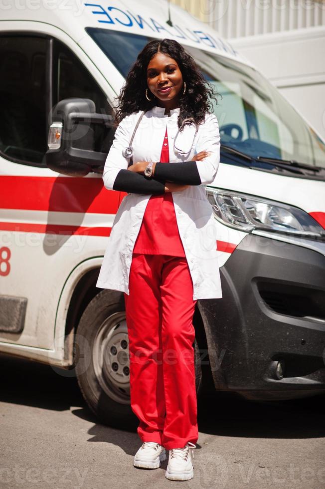 Afroamerikanische Sanitäterin, die vor einem Krankenwagen steht. foto