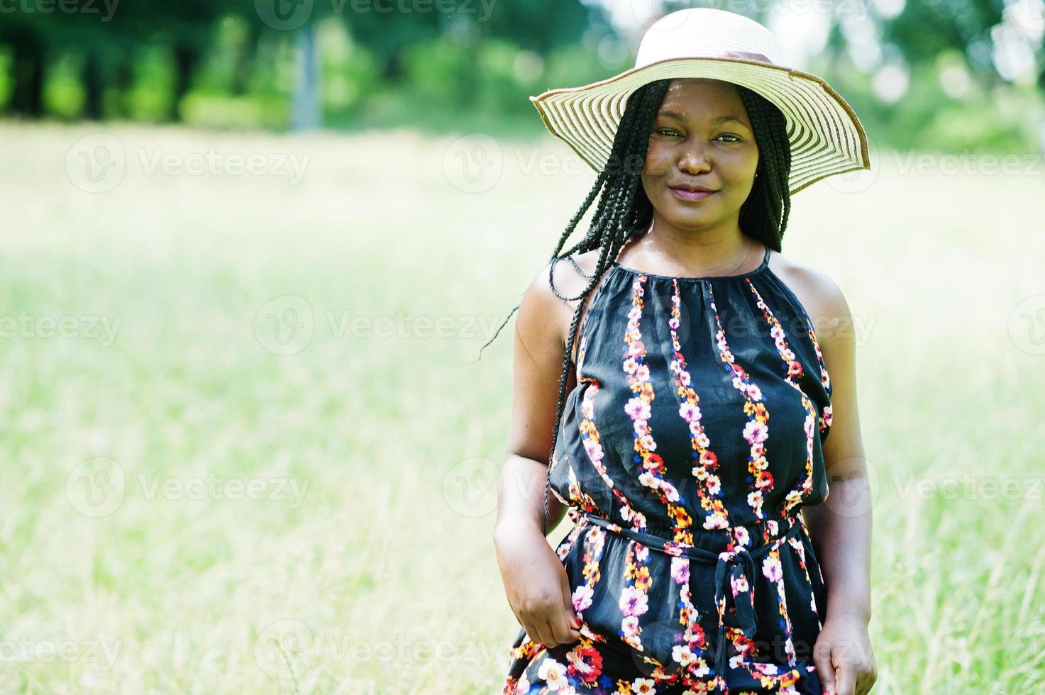 Porträt einer wunderschönen afroamerikanischen Frau der 20er Jahre mit Sommerhut, die auf grünem Gras im Park posiert. foto