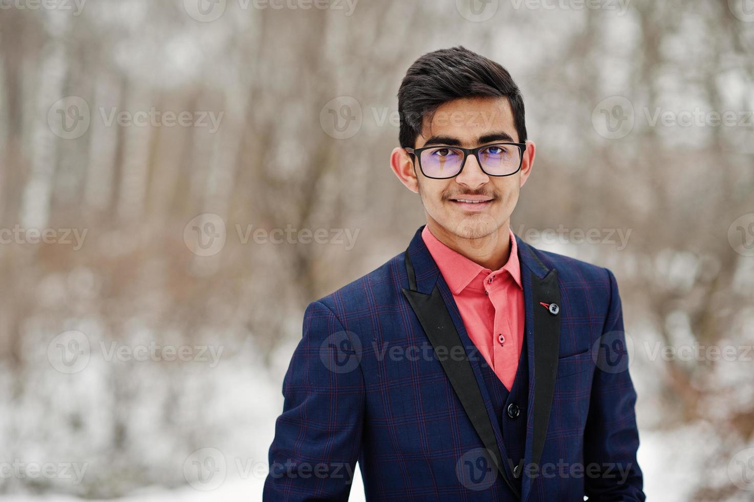 stilvoller indischer studentenmann in anzug und brille posierte am wintertag im freien. foto