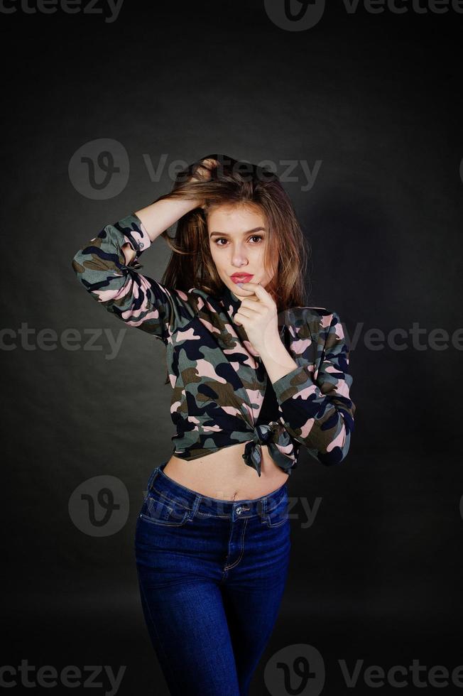 hübsches brünettes mädchen trägt militärisches hemd und jeans und posiert im studio vor grauem hintergrund. Studio-Model-Porträt. foto