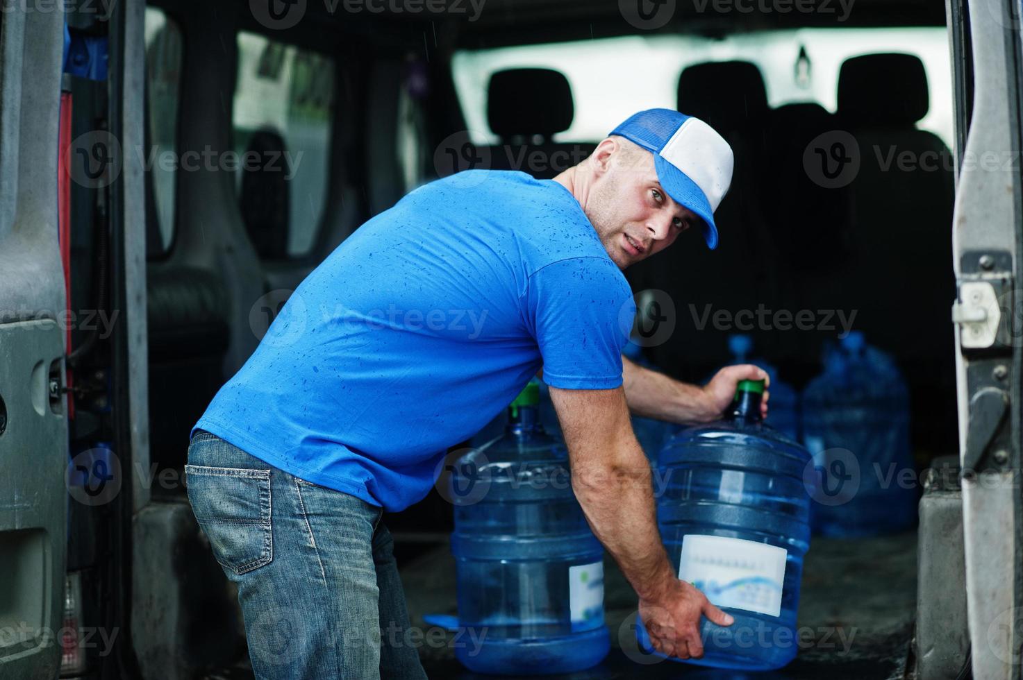 lieferbote im vorderen frachtwagen, der flaschen wasser liefert. foto