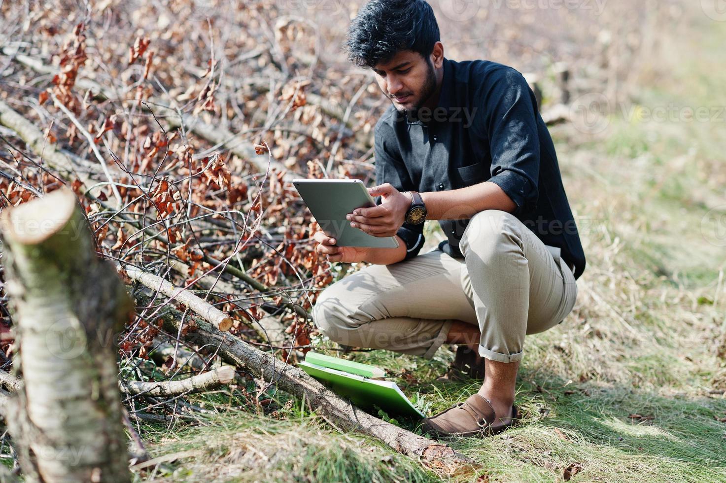 Südasiatischer Agronom Bauer mit Klemmbrett, der geschnittene Bäume im Bauerngarten inspiziert. landwirtschaftliches Produktionskonzept. foto