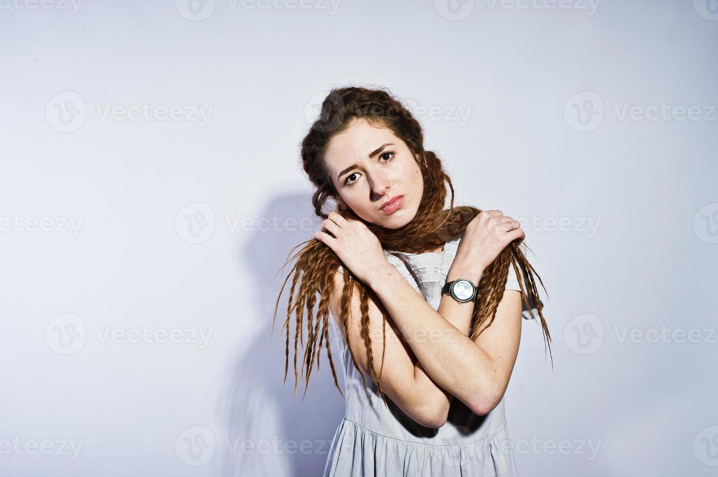 Studio-Shooting von Mädchen in grauem Kleid mit Dreads-Zöpfen auf weißem Hintergrund. foto