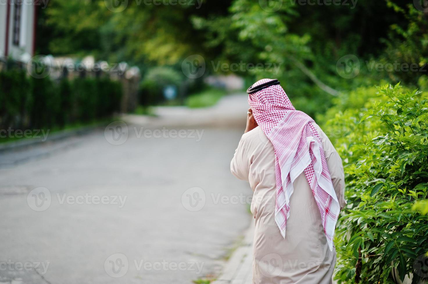 Rückseite des arabischen Geschäftsmannes aus dem Nahen Osten, der auf der Straße posiert und mit dem Handy spricht. foto