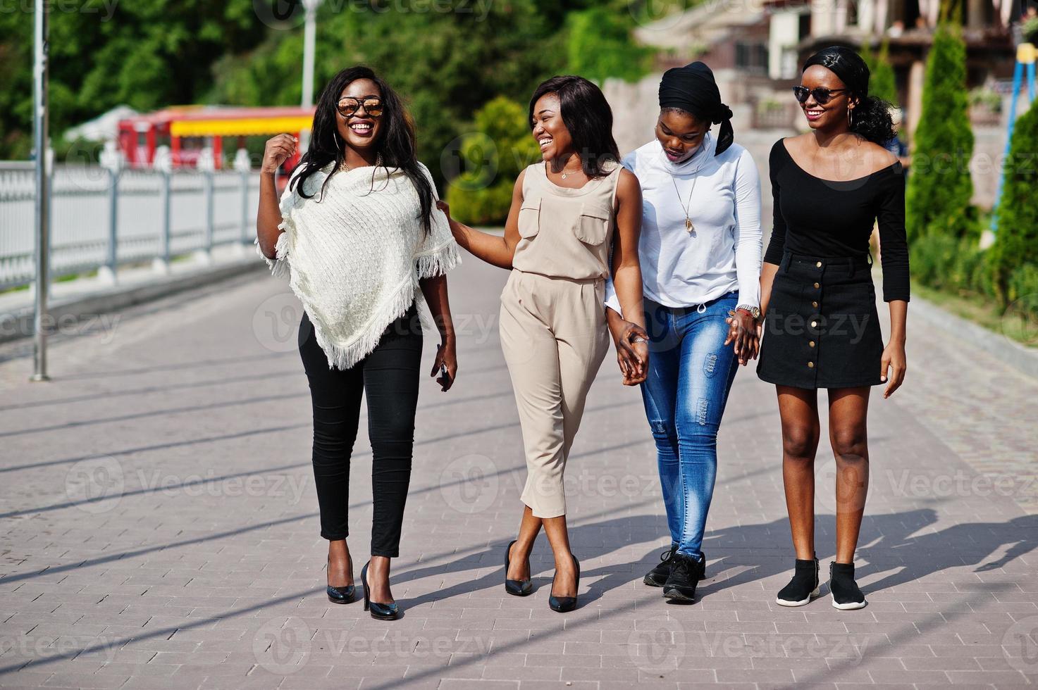 Gruppe von vier afroamerikanischen Mädchen, die an einem sonnigen Tag in der Stadt spazieren gehen. foto