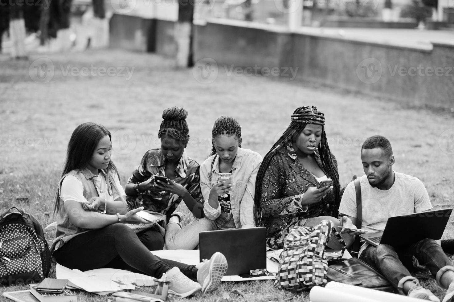 Gruppe von fünf afrikanischen College-Studenten, die gemeinsam Zeit auf dem Campus des Universitätshofs verbringen. schwarze afro-freunde, die mit handys machen. Thema Bildung. foto