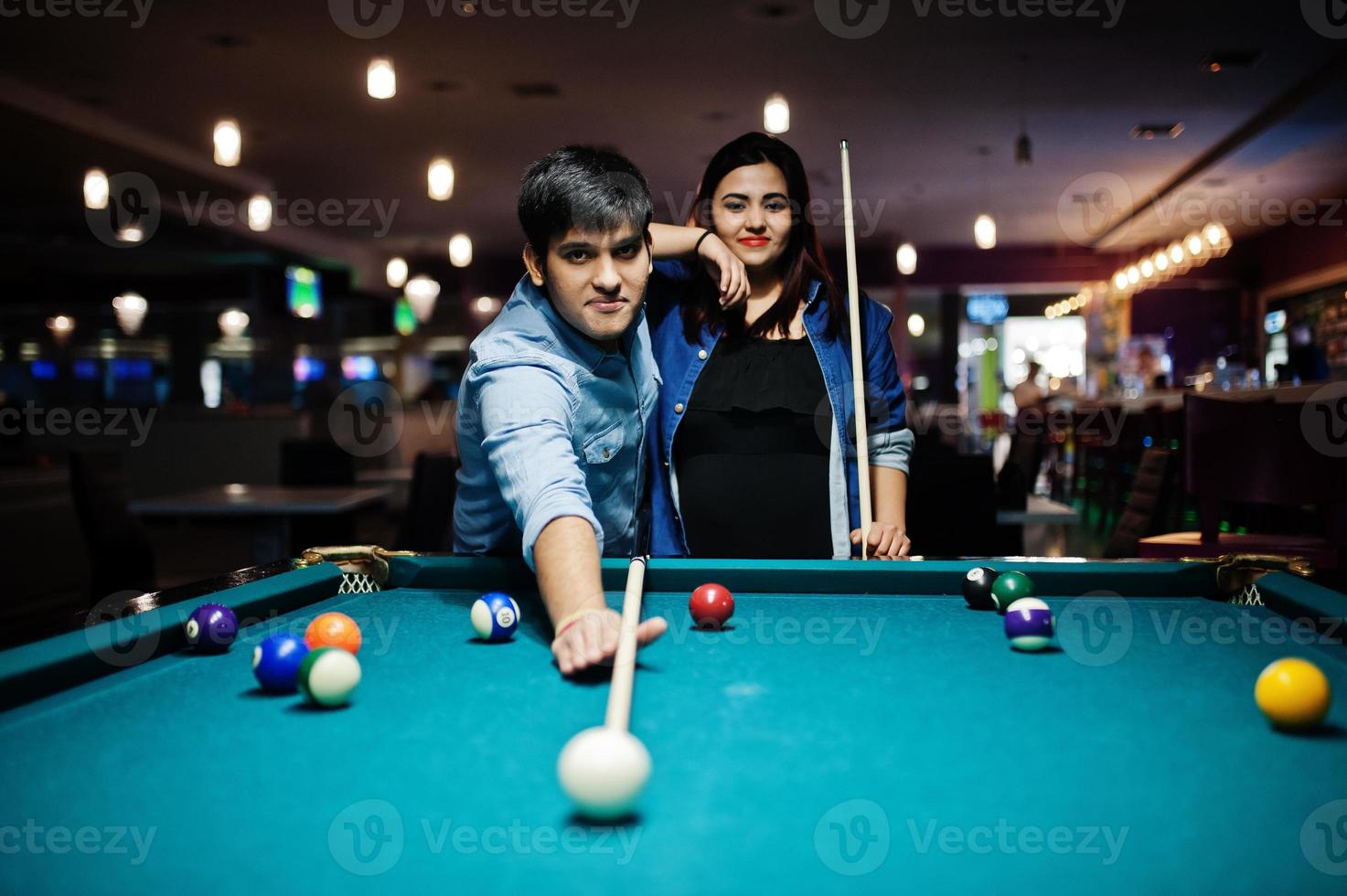 Stilvolles asiatisches Paar trägt Jeans und spielt Billard an der Bar. foto