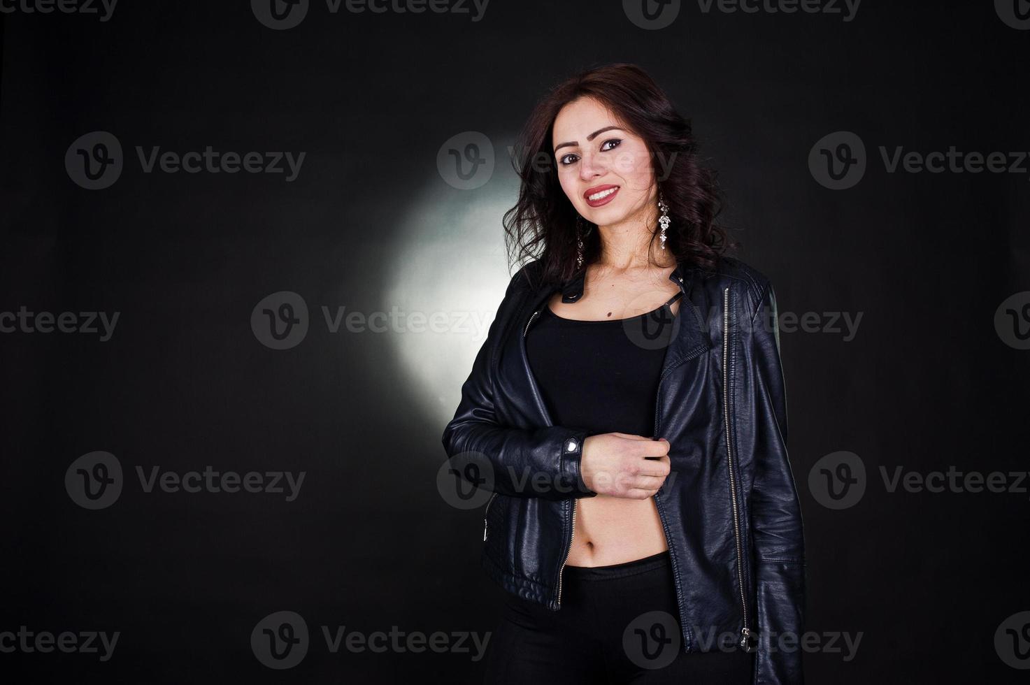 Studioporträt eines sexy brünetten Mädchens in schwarzer Lederjacke vor schwarzem Hintergrund. foto