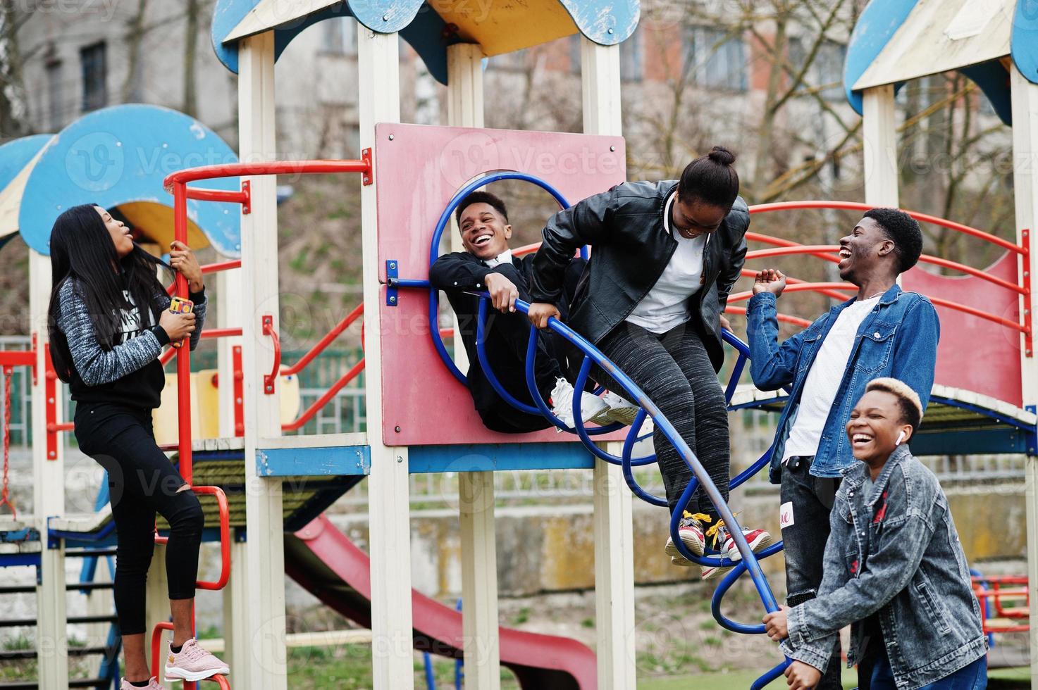 junge tausendjährige afrikanische freunde auf spielplatz, rutsche und schaukel. glückliche schwarze leute, die zusammen spaß haben. generation z freundschaftskonzept. foto